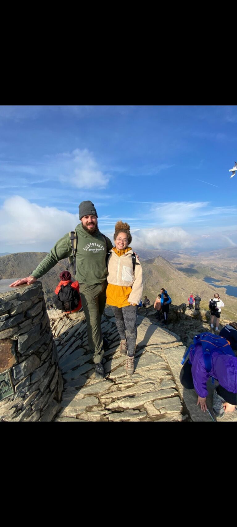 Climbers enjoying a mountain summit with scenic views and clear blue sky.