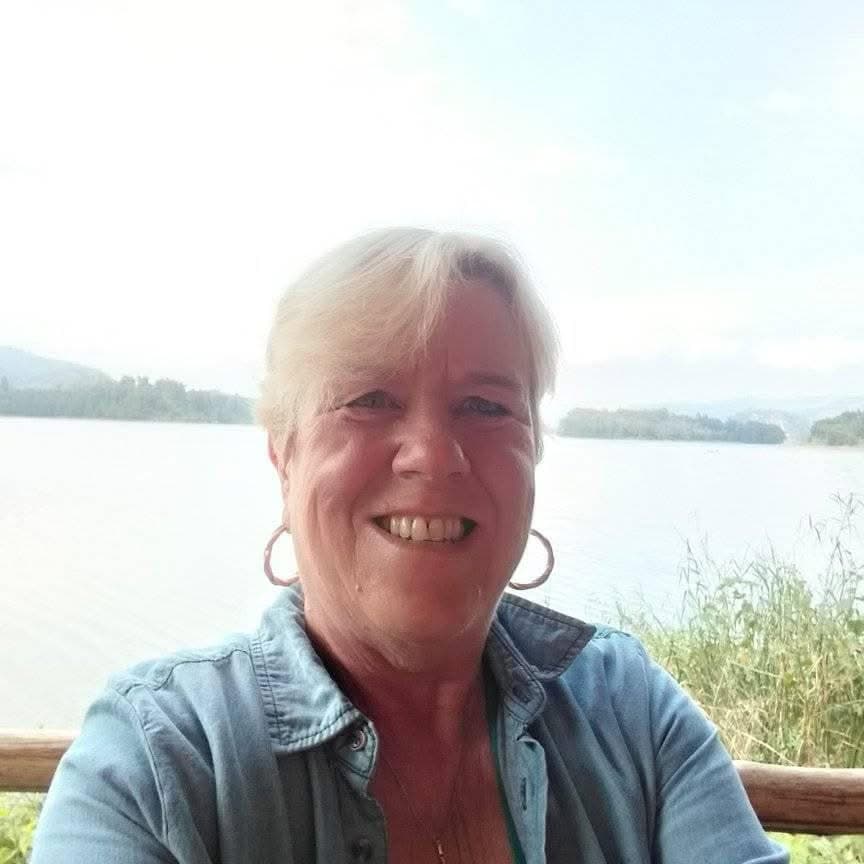 Woman smiling outdoors near a lake, promoting melanoma awareness and skin health.