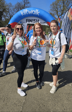 Bright-hearted Kiltwalkers celebrating at Glasgow finish line for melanoma awareness and skin cancer.