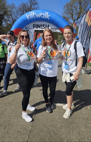 Bright-hearted Kiltwalkers celebrating at Glasgow finish line for melanoma awareness and skin cancer.
