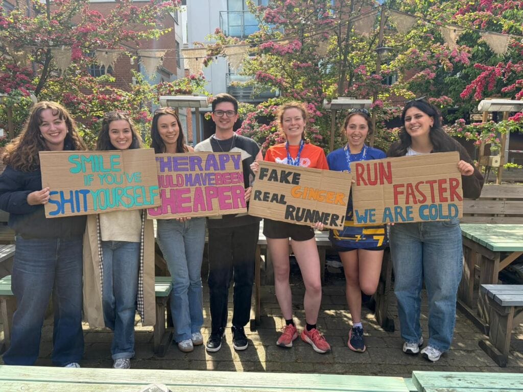 Group of young people holding protest signs outdoors in a garden setting.