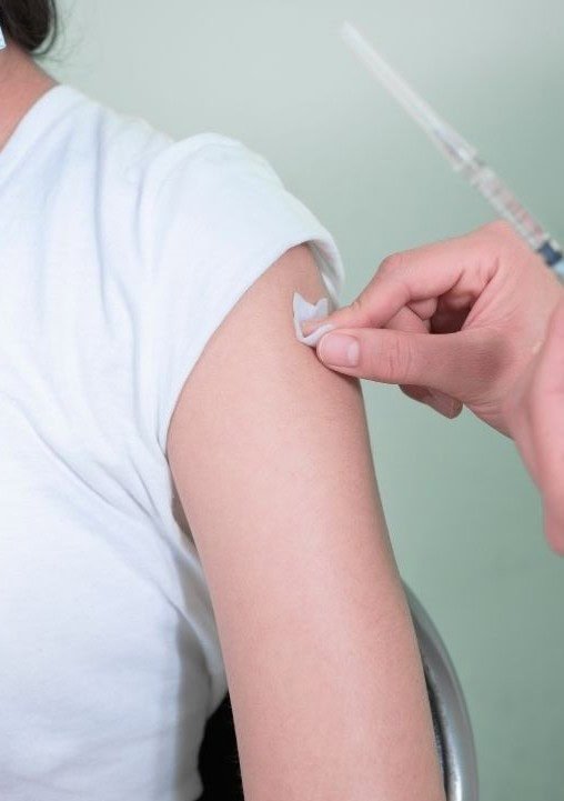 Person receiving a vaccination shot in upper arm for melanoma prevention.