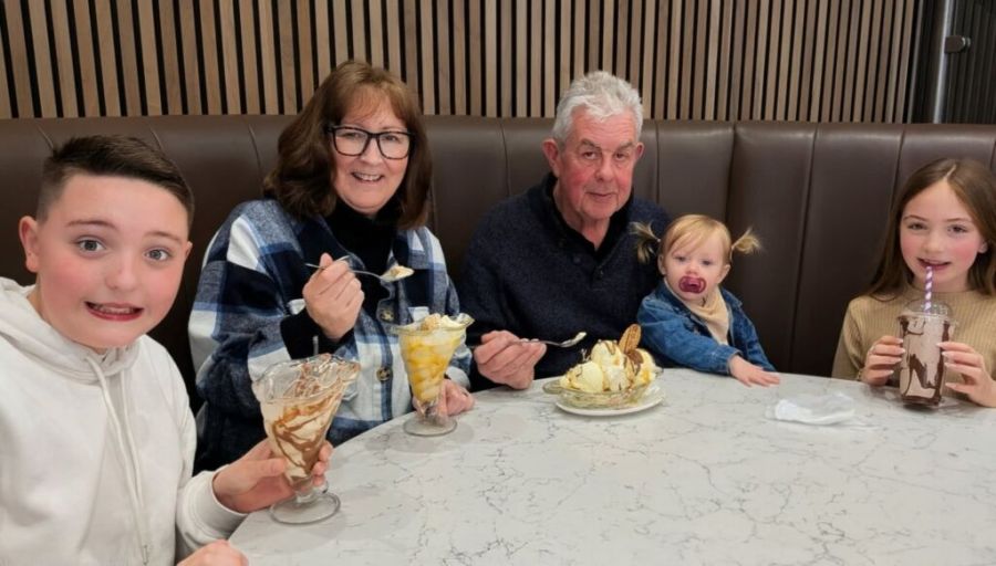 Family enjoying ice cream at a restaurant table for Melanoma UK awareness.