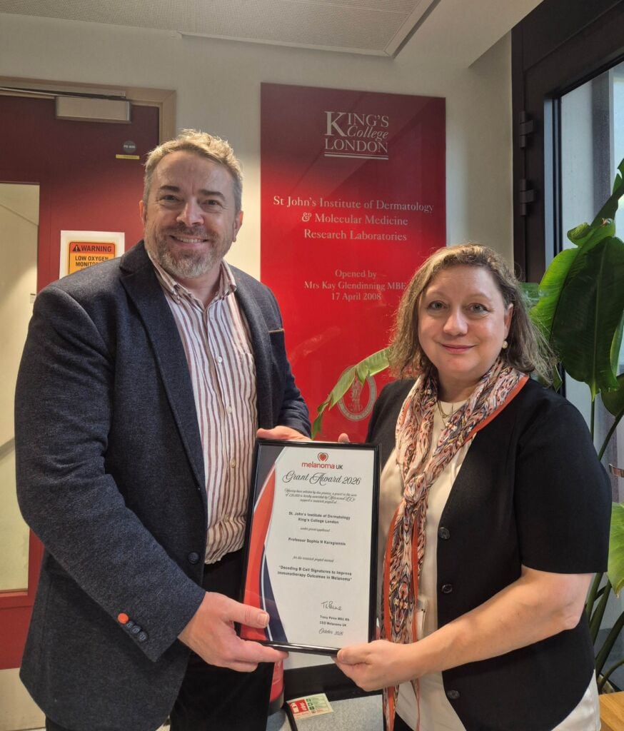 Two professionals holding a melanoma research award at Kings College London.